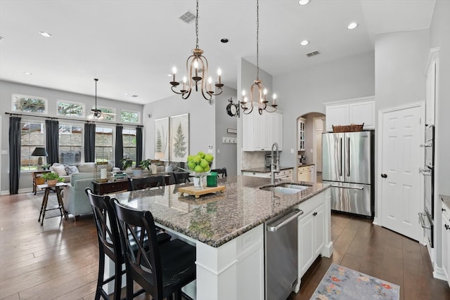 1416 Basil Dr, Flower Mound, TX 75028 - kitchen with appliances with stainless steel finishes, a sink, arched walkways, a towering ceiling, and dark wood-type flooring