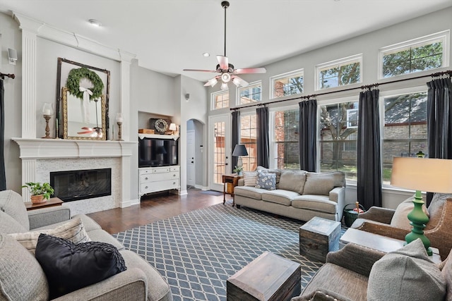 1416 Basil Dr, Flower Mound, TX 75028 - living room featuring wood finished floors, ceiling fan, arched walkways, a glass covered fireplace, and a high ceiling