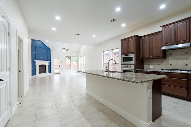 10909 Blake Gdns, Mckinney, TX 75072 - kitchen featuring stainless steel appliances, a sink, under cabinet range hood, stone countertops, and ceiling fan