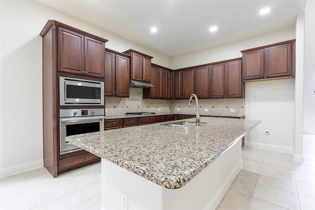 10909 Blake Gdns, Mckinney, TX 75072 - kitchen featuring stainless steel appliances, a sink, backsplash, light stone counters, and an island with sink