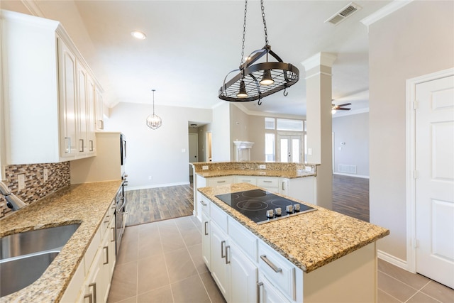 3015 Oak Dr, Rockwall, TX 75032 - kitchen featuring black electric stovetop, a sink, a kitchen island, baseboards, and crown molding