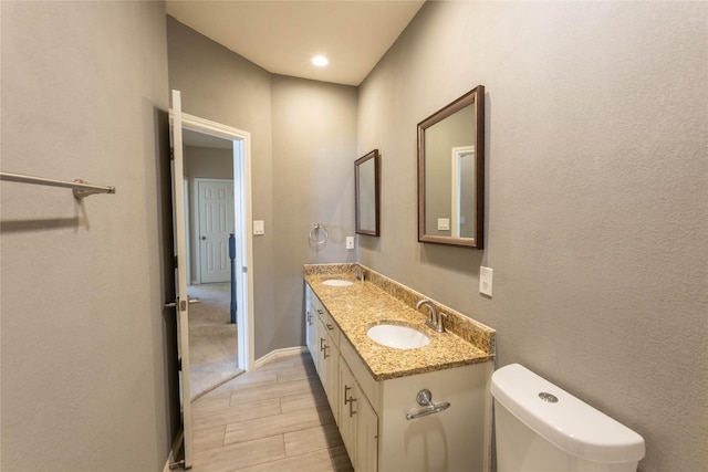 3015 Oak Dr, Rockwall, TX 75032 - bathroom featuring double vanity, toilet, wood tiled floors, and baseboards