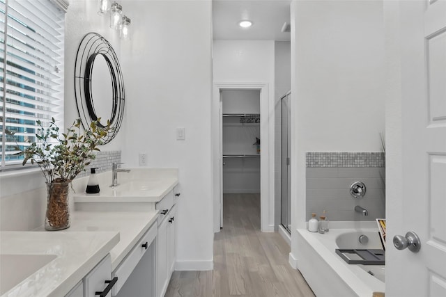 1805 13th St, Argyle, TX 76226 - full bathroom featuring a stall shower, double vanity, a bath, wood finished floors, and a walk in closet