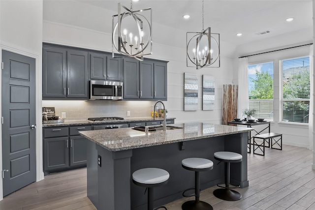 1805 13th St, Argyle, TX 76226 - kitchen with a sink, stainless steel appliances, a chandelier, light wood-type flooring, and light stone countertops