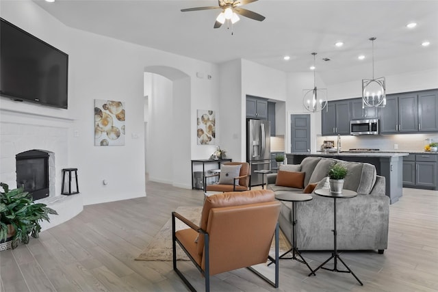 1805 13th St, Argyle, TX 76226 - living room with ceiling fan, recessed lighting, light wood-style flooring, arched walkways, and a glass covered fireplace