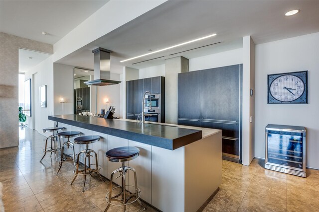 1717 Arts Plz Unit 2202, Dallas, TX 75201 - kitchen featuring island exhaust hood, a breakfast bar area, dark countertops, and beverage cooler