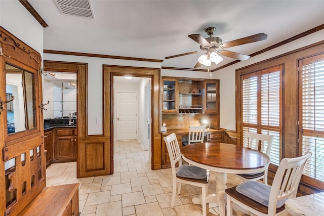 3308 Runabout Ct, Plano, TX 75023 - dining room featuring a ceiling fan, wainscoting, light stone finish flooring, and crown molding