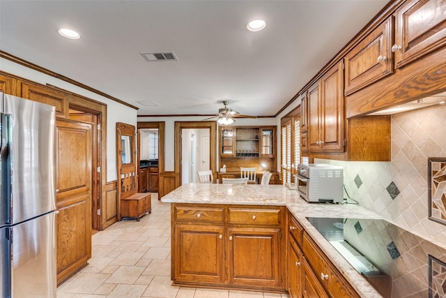 3308 Runabout Ct, Plano, TX 75023 - kitchen with freestanding refrigerator, a peninsula, brown cabinets, ornamental molding, and ceiling fan