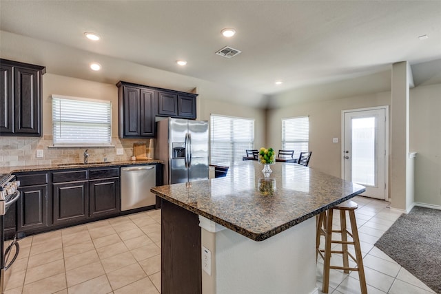 2613 Hillrich Dr, Anna, TX 75409 - kitchen featuring appliances with stainless steel finishes, a sink, a kitchen bar, light tile patterned floors, and a center island