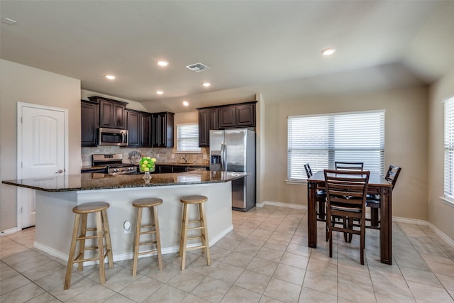 2613 Hillrich Dr, Anna, TX 75409 - kitchen with appliances with stainless steel finishes, a kitchen island, backsplash, dark brown cabinets, and vaulted ceiling