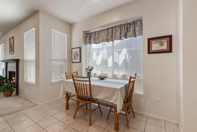 3942 Luke Ln, Carrollton, TX 75007 - dining area with light tile patterned floors, a textured ceiling, a tiled fireplace, and baseboards