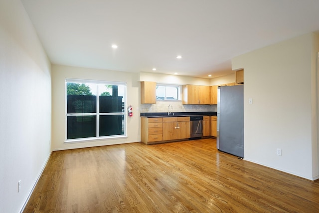4616 W Lovers Ln Unit 119, Dallas, TX 75209 - kitchen with appliances with stainless steel finishes, a sink, dark countertops, light wood finished floors, and backsplash