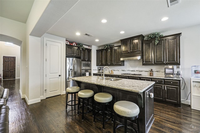 955 Champions Way, Roanoke, TX 76262 - kitchen with a sink, appliances with stainless steel finishes, dark wood-style floors, a breakfast bar, and arched walkways