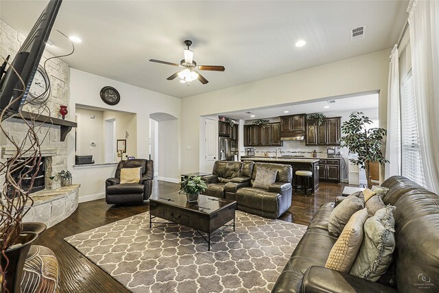 955 Champions Way, Roanoke, TX 76262 - living area featuring ceiling fan, arched walkways, dark wood-style flooring, a stone fireplace, and baseboards