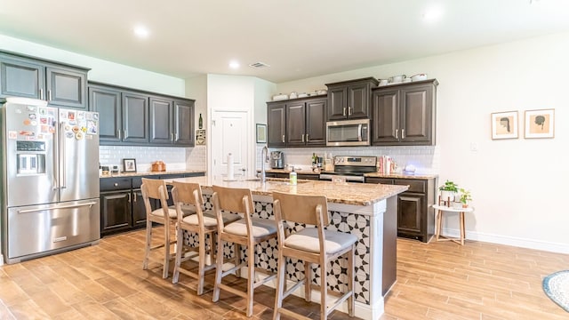 1715 Swale Ln, Granbury, TX 76049 - kitchen with stainless steel appliances, light wood finished floors, a kitchen breakfast bar, backsplash, and recessed lighting