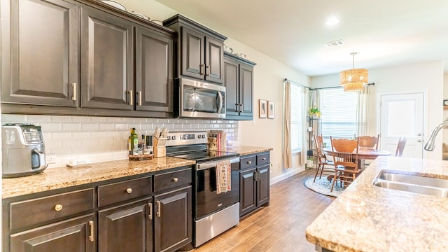 1715 Swale Ln, Granbury, TX 76049 - kitchen with appliances with stainless steel finishes, a sink, light wood-style flooring, decorative backsplash, and baseboards