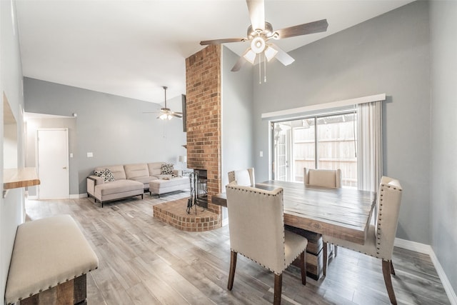 5622 Polo Club Dr, Arlington, TX 76017 - dining room featuring a ceiling fan, light wood-style flooring, a brick fireplace, high vaulted ceiling, and baseboards