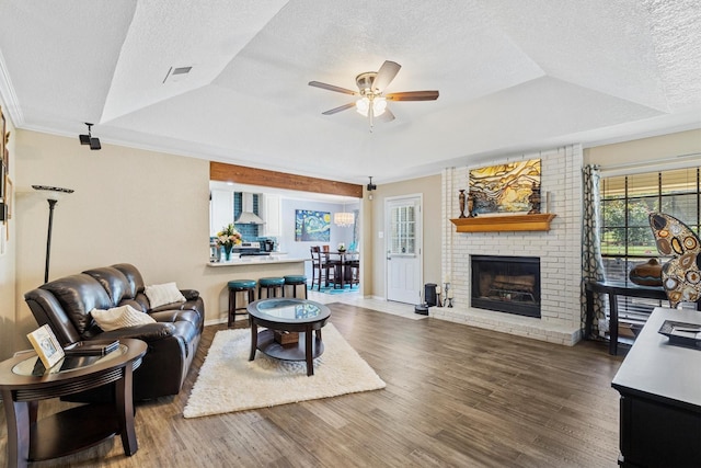 5240 Hill Ridge Dr, Fort Worth, TX 76135 - living area with a tray ceiling, a textured ceiling, ceiling fan, wood finished floors, and a brick fireplace