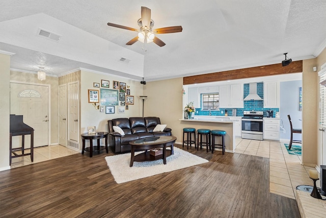 5240 Hill Ridge Dr, Fort Worth, TX 76135 - living room featuring light wood-style floors, ceiling fan, baseboards, ornamental molding, and a textured ceiling