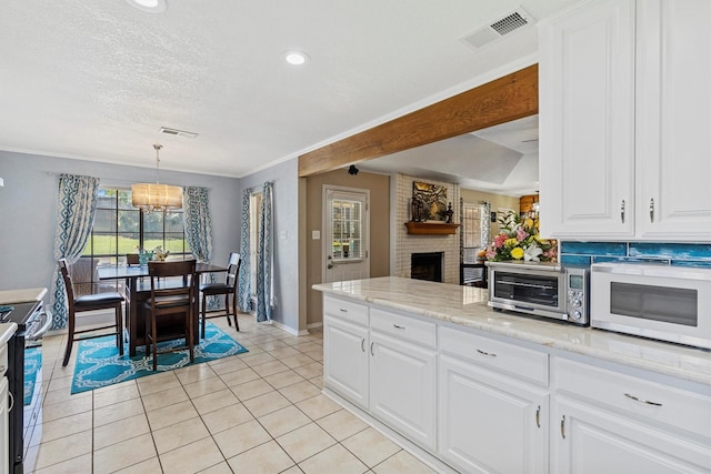 5240 Hill Ridge Dr, Fort Worth, TX 76135 - kitchen with white microwave, electric stove, a chandelier, baseboards, and white cabinetry