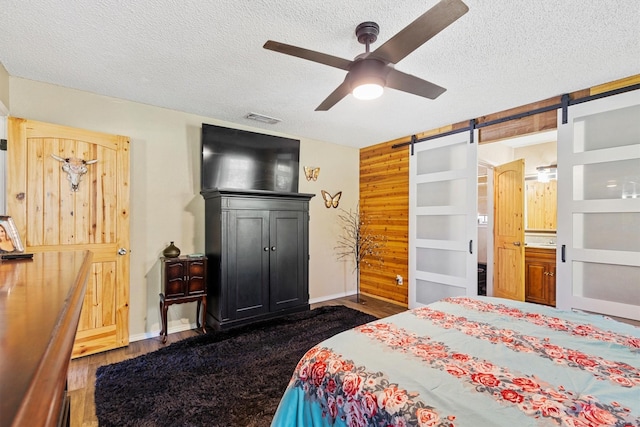 5240 Hill Ridge Dr, Fort Worth, TX 76135 - bedroom featuring a textured ceiling, wood finished floors, a barn door, a ceiling fan, and baseboards