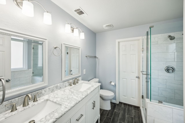 208 Bluefinch, Little Elm, TX 75068 - bathroom with double vanity, toilet, a stall shower, and wood finish floors