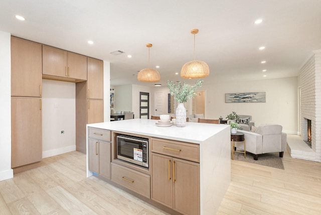 7818 Rolling Acres Dr, Dallas, TX 75248 - kitchen with stainless steel microwave, light wood-type flooring, open floor plan, recessed lighting, and a brick fireplace