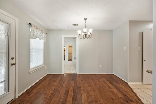 2311 Markland St, Irving, TX 75060 - unfurnished dining area with a chandelier, wood finished floors, and baseboards