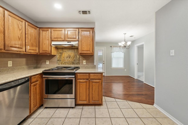 2311 Markland St, Irving, TX 75060 - kitchen featuring appliances with stainless steel finishes, under cabinet range hood, a chandelier, backsplash, and light countertops