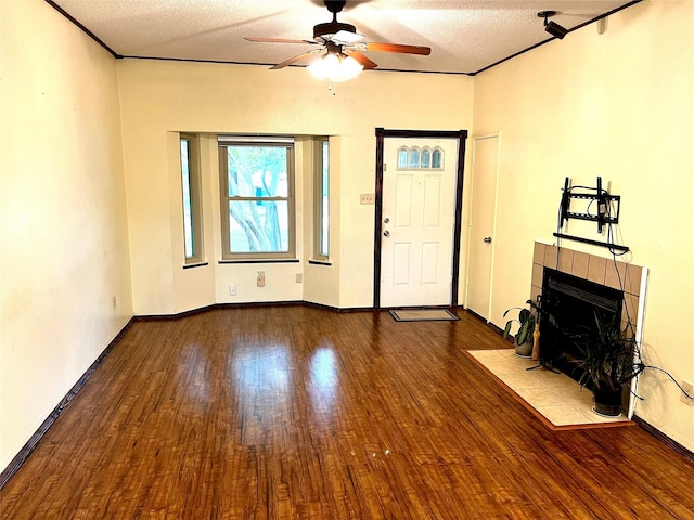 617 Reed St, Roanoke, TX 76262 - unfurnished living room featuring wood finished floors, a ceiling fan, a tiled fireplace, a textured ceiling, and baseboards