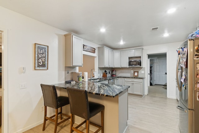 213 Lacewell St, Jacksboro, TX 76458 - kitchen featuring appliances with stainless steel finishes, a peninsula, light wood-style floors, a sink, and a kitchen breakfast bar