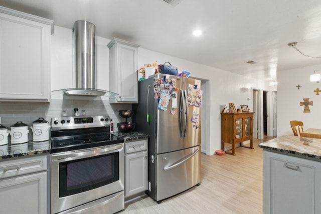 213 Lacewell St, Jacksboro, TX 76458 - kitchen with stainless steel appliances, wall chimney exhaust hood, backsplash, dark stone counters, and light wood-style flooring