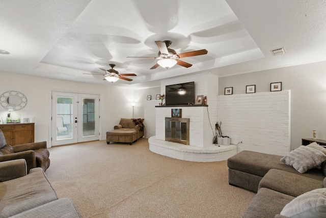 213 Lacewell St, Jacksboro, TX 76458 - living room featuring a raised ceiling, carpet, a brick fireplace, a ceiling fan, and french doors