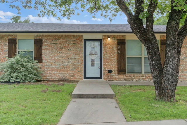 213 Lacewell St, Jacksboro, TX 76458 - doorway to property featuring brick siding and a lawn