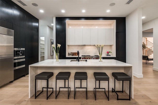 6075 Jordan Way, Frisco, TX 75034 - kitchen featuring dark cabinets, modern cabinets, stainless steel built in refrigerator, a sink, and a breakfast bar area