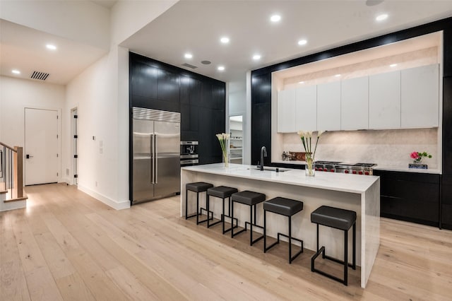 6075 Jordan Way, Frisco, TX 75034 - kitchen with stainless steel built in refrigerator, dark cabinetry, a breakfast bar area, modern cabinets, and recessed lighting