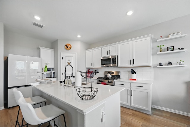 1229 Sequoia Ln, Princeton, TX 75407 - kitchen featuring appliances with stainless steel finishes, light countertops, decorative backsplash, white cabinetry, and a center island with sink