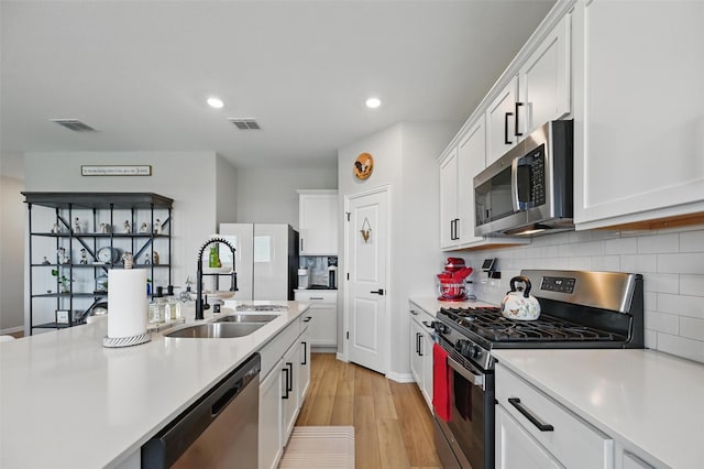 1229 Sequoia Ln, Princeton, TX 75407 - kitchen featuring stainless steel appliances, a sink, light countertops, light wood-type flooring, and white cabinetry