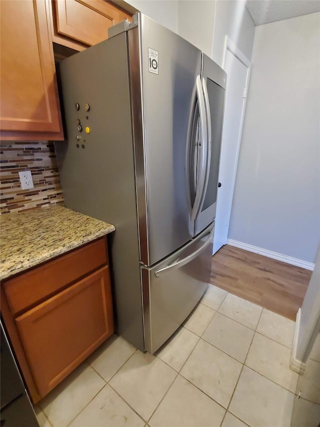 12480 Abrams Rd, Dallas, TX 75243 - kitchen featuring freestanding refrigerator, light tile patterned floors, decorative backsplash, light stone countertops, and baseboards