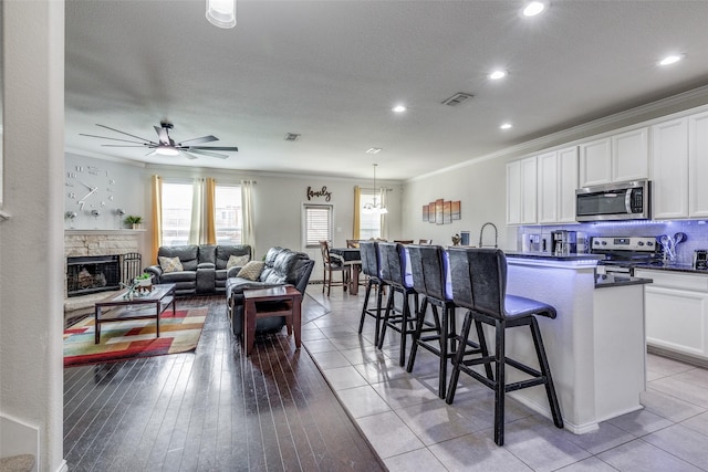 7828 Tudanca Trl, Fort Worth, TX 76131 - kitchen featuring appliances with stainless steel finishes, ornamental molding, a breakfast bar, white cabinetry, and a kitchen island with sink