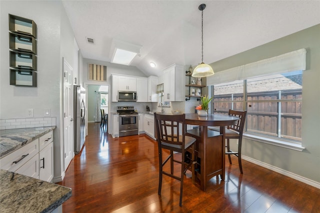 11505 Canoe Rd, Frisco, TX 75035 - dining room featuring lofted ceiling, dark wood-type flooring, a skylight, and baseboards