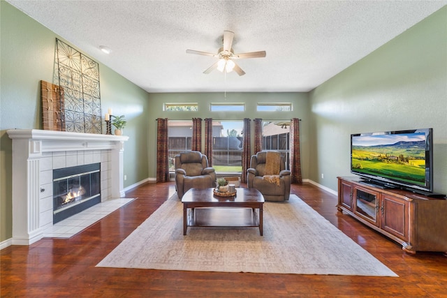 11505 Canoe Rd, Frisco, TX 75035 - living area featuring ceiling fan, a tiled fireplace, a textured ceiling, wood finished floors, and baseboards