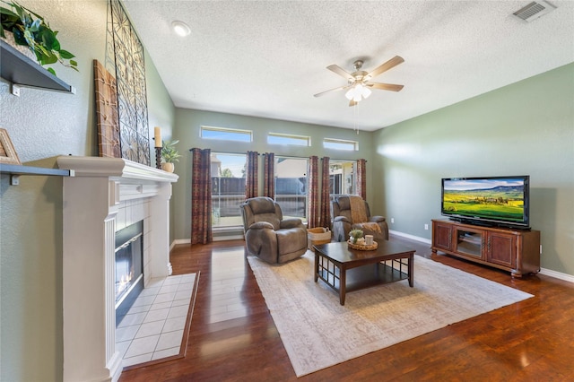 11505 Canoe Rd, Frisco, TX 75035 - living area with ceiling fan, wood finished floors, a tiled fireplace, a textured ceiling, and baseboards
