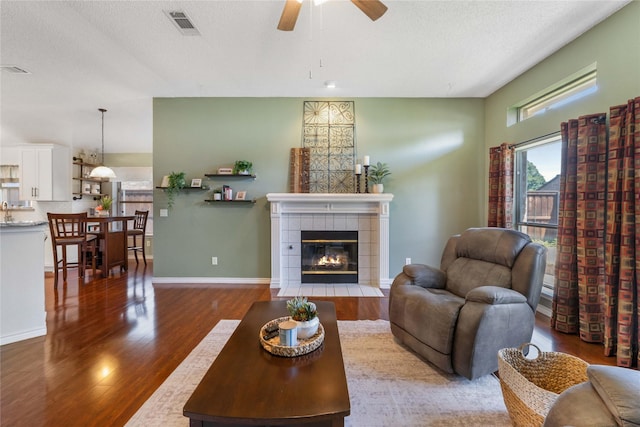 11505 Canoe Rd, Frisco, TX 75035 - living room with wood finished floors, a ceiling fan, a tile fireplace, a textured ceiling, and baseboards