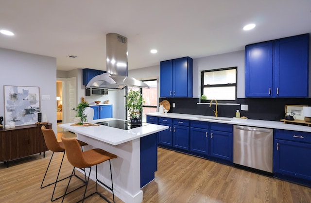 6519 Club Wood, Dallas, TX 75237 - kitchen featuring stainless steel appliances, island range hood, a sink, blue cabinets, and a breakfast bar area