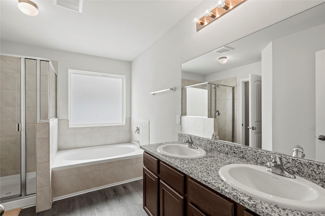 5649 Willamette Dr, Fort Worth, TX 76119 - full bathroom featuring wood finished floors, a shower stall, a bath, and double vanity