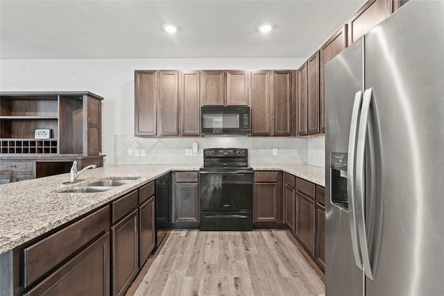5649 Willamette Dr, Fort Worth, TX 76119 - kitchen featuring black appliances, a sink, light wood finished floors, light stone counters, and decorative backsplash
