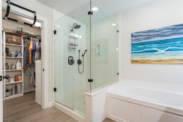10443 County Road 3407, Brownsboro, TX 75756 - bathroom with a stall shower, a bath, a walk in closet, and wood finished floors