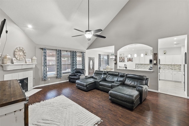 7113 Sundance Ln, Fort Worth, TX 76179 - living area featuring a ceiling fan, wood finished floors, a tile fireplace, high vaulted ceiling, and arched walkways