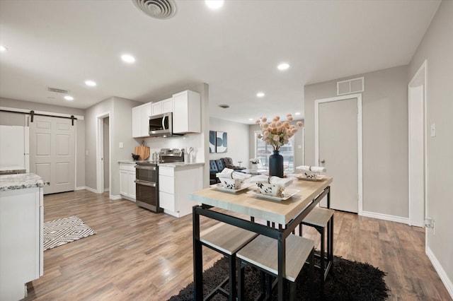 14053 Stardust Ln, Farmers Branch, TX 75234 - dining space with a barn door, baseboards, light wood-style floors, and recessed lighting